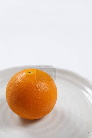 Téléchargez les photos : Orange entière sur une assiette blanche - en image libre de droit