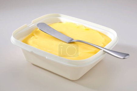 Téléchargez les photos : Récipient en plastique ouvert avec beurre et cuillère - en image libre de droit