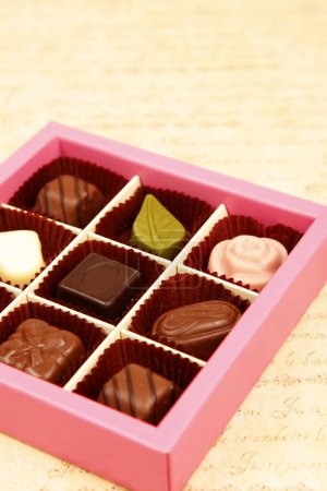Foto de Un primer plano vertical de un caramelo de chocolate con caja de chocolate rosa - Imagen libre de derechos