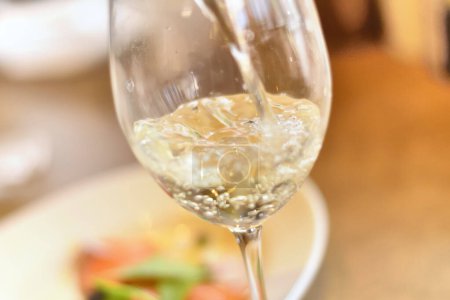 Photo for Wineglass with white wine on wooden table in cafe - Royalty Free Image