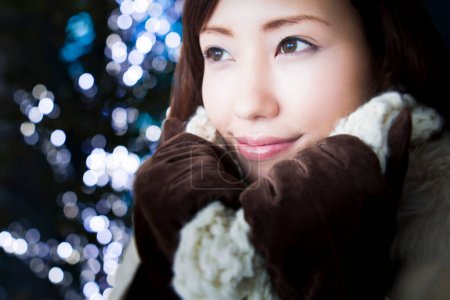Téléchargez les photos : Asiatique jeune femme en vêtements chauds dans la rue d'hiver la nuit, bokeh lumières sur fond - en image libre de droit