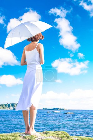 Téléchargez les photos : Jeune femme avec parapluie au bord de la mer - en image libre de droit
