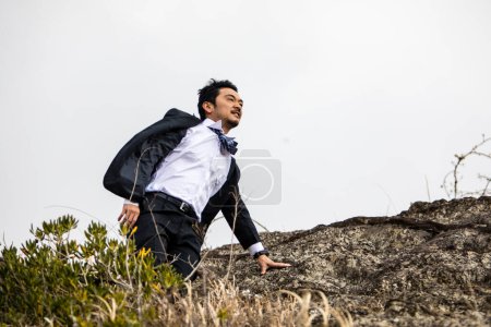 Foto de Joven asiático hombre de negocios en rocky playa - Imagen libre de derechos