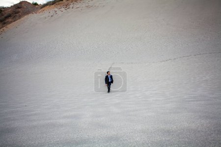Téléchargez les photos : Asiatique homme d'affaires marche sur sable fin plage - en image libre de droit