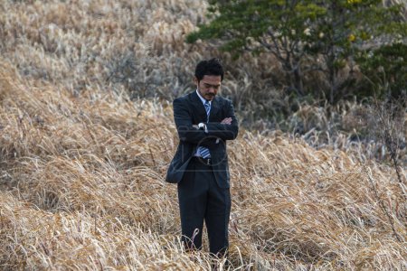 Foto de Asiático hombre de negocios en formal traje de pie en un campo - Imagen libre de derechos