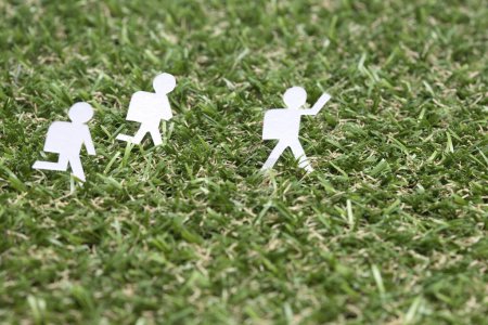 Photo for White paper human figures on the green grass field - Royalty Free Image