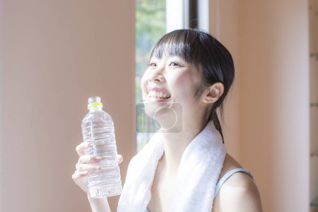 Foto de Mujer asiática bebiendo agua después del entrenamiento en el gimnasio - Imagen libre de derechos