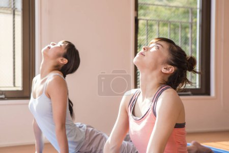 Foto de Jóvenes mujeres asiáticas haciendo ejercicio juntos en casa en sala de estar - Imagen libre de derechos
