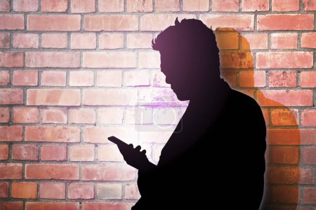 Téléchargez les photos : Silhouette d'un homme contre un mur de briques - en image libre de droit