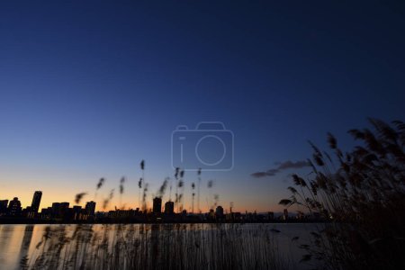 Téléchargez les photos : Magnifique coucher de soleil sur le lac avec la ville - en image libre de droit
