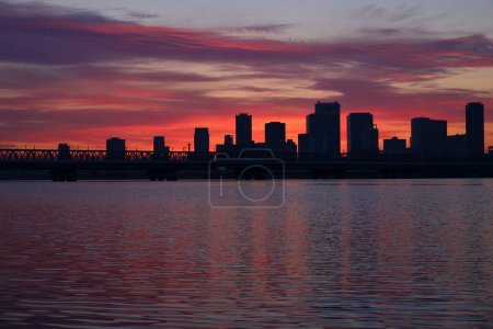 schöner Sonnenuntergang über der Skyline der Stadt und Spiegelung im Wasser   