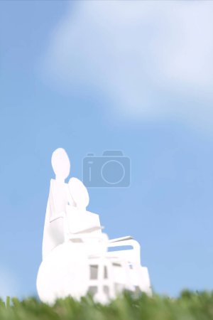 Photo for Cut out paper human figure carrying person on wheelchair, family care and support concept background - Royalty Free Image