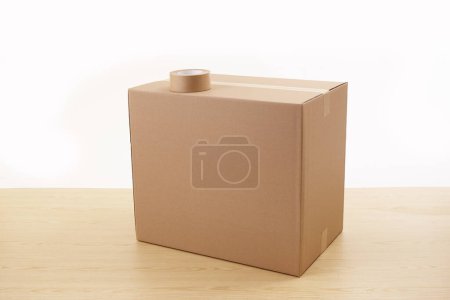 Foto de Caja de cartón y cinta adhesiva sobre mesa de madera aislada sobre fondo blanco - Imagen libre de derechos