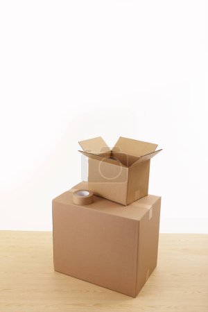 Foto de Cajas de cartón y cinta adhesiva sobre mesa de madera aislada sobre fondo blanco - Imagen libre de derechos