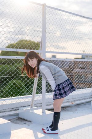 Téléchargez les photos : Portrait d'adolescente asiatique en uniforme scolaire au parapet en métal - en image libre de droit