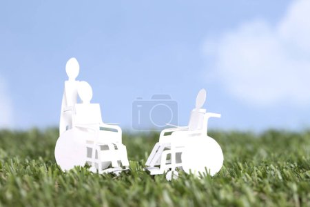 Foto de Recortar la figura humana de papel que lleva a la persona en silla de ruedas, cuidado familiar y fondo concepto de apoyo - Imagen libre de derechos