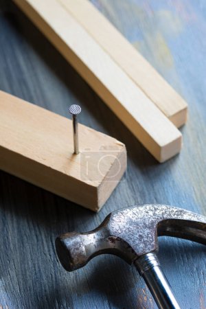 Foto de Tablero de madera y clavos sobre un fondo de madera con martillo - Imagen libre de derechos