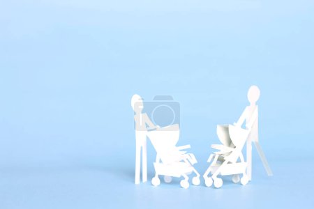 Foto de Fondo de concepto de maternidad con mujeres de papel recortado con cochecito sobre fondo azul - Imagen libre de derechos