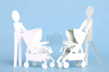 Foto de Fondo de concepto de maternidad con mujeres de papel recortado con cochecito sobre fondo azul - Imagen libre de derechos