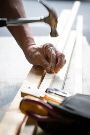 Téléchargez les photos : Homme dans l'atelier en utilisant le marteau et l'ongle - en image libre de droit