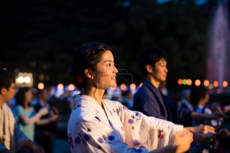 Téléchargez les photos : Jeune couple japonais vêtu de kimono traditionnel dansant dans le parc du soir - en image libre de droit