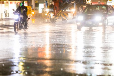 Foto de Coches que conducen por la calle de la ciudad durante la lluvia por la noche - Imagen libre de derechos