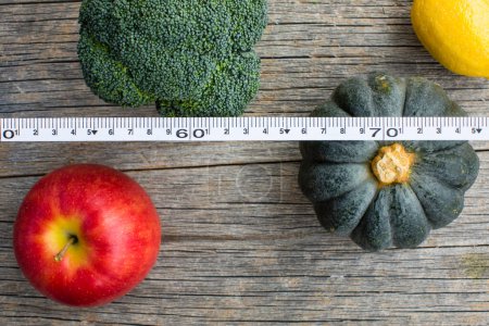 Foto de Vista superior de frutas y verduras con cinta métrica sobre fondo de madera, fondo de concepto de dieta - Imagen libre de derechos