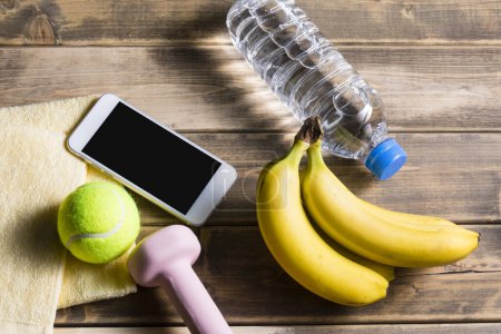 Téléchargez les photos : Vue du smartphone avec équipement sportif sur fond bois, concept fitness et sport - en image libre de droit