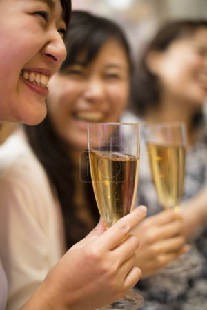 Foto de Feliz joven asiática bebiendo champán en una fiesta - Imagen libre de derechos