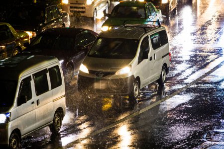 Téléchargez les photos : Voitures conduisant le long de la rue de la ville pendant la pluie la nuit - en image libre de droit
