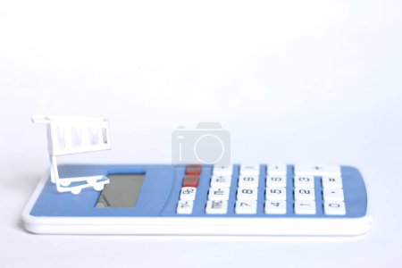 Photo for Shopping trolley and calculator isolated on background - Royalty Free Image