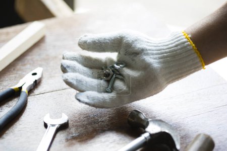 Téléchargez les photos : Main d'homme avec gants tenant écrous et vis - en image libre de droit