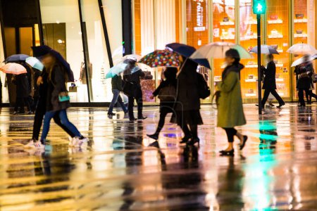 Téléchargez les photos : Personnes marchant dans la rue pendant la soirée pluvieuse - en image libre de droit