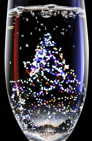 Photo for Glass with champagne in front of christmas tree bokeh lights - Royalty Free Image
