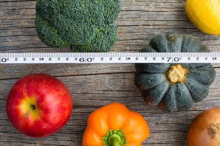 Téléchargez les photos : Vue du dessus des fruits et légumes avec ruban à mesurer sur fond en bois, arrière-plan concept alimentation - en image libre de droit