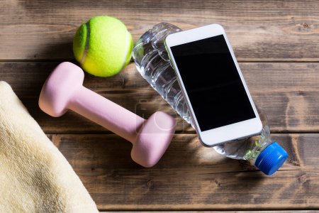 Téléchargez les photos : Vue du smartphone avec équipement sportif sur fond bois, concept fitness et sport - en image libre de droit