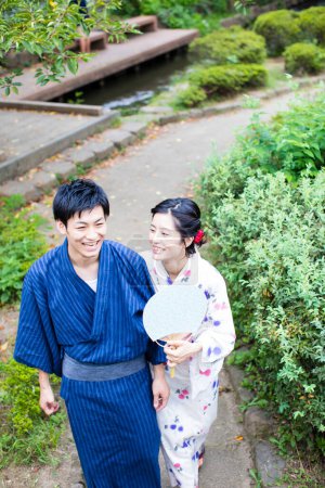 Photo for Young Japanese couple wearing traditional kimono in summer park - Royalty Free Image