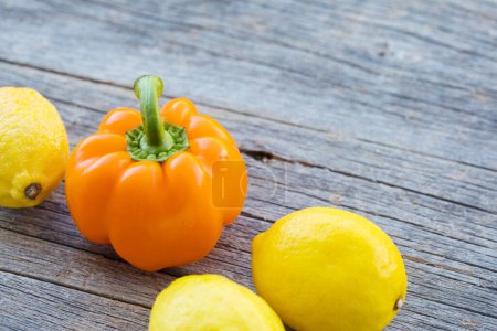 Photo for Orange bell pepper and lemons on wooden background - Royalty Free Image