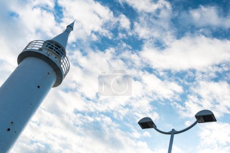 Photo for White lighthouse against blue cloudy sky. - Royalty Free Image