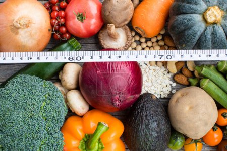 Téléchargez les photos : Vue du dessus des fruits et légumes avec ruban à mesurer sur fond en bois, arrière-plan concept alimentation - en image libre de droit
