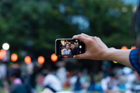 Photo for Young Japanese couple wearing traditional kimono taking selfie on smartphone in evening park - Royalty Free Image