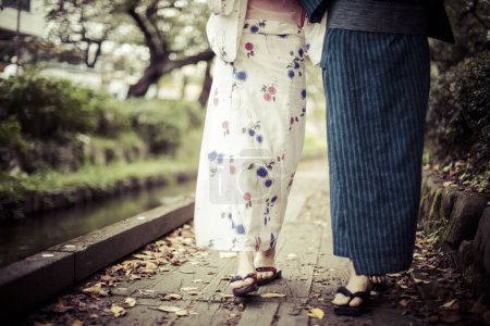 Téléchargez les photos : Section basse de jeune couple japonais portant kimono traditionnel dans le parc d'été - en image libre de droit
