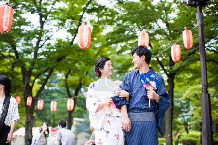 Photo for Young Japanese couple wearing traditional kimono and holding Asian fans in the park - Royalty Free Image