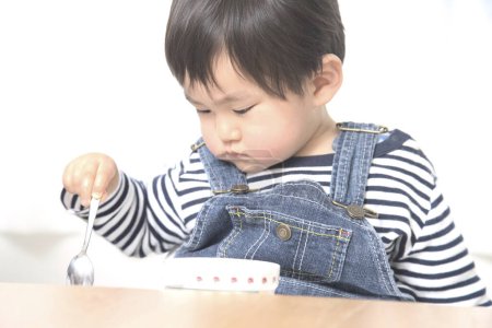 Téléchargez les photos : Portrait de mignon petit asiatique garçon manger à la maison - en image libre de droit