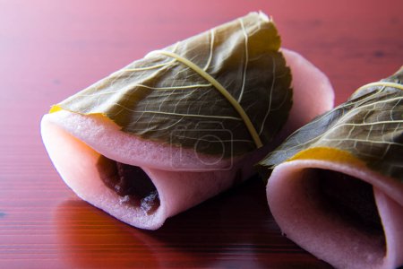 Foto de Sakuramochi es una confección japonesa (wagashi) que consiste en un dulce pastel de arroz de color rosa (mochi) con relleno de pasta de frijol rojo (anko), envuelto en una hoja de flor de cerezo en escabeche (sakura) - Imagen libre de derechos