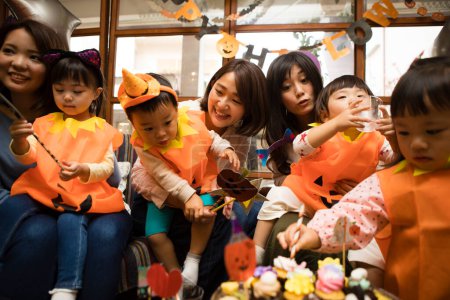 Foto de Asiático jóvenes madres y su lindo poco niños celebrando Halloween - Imagen libre de derechos