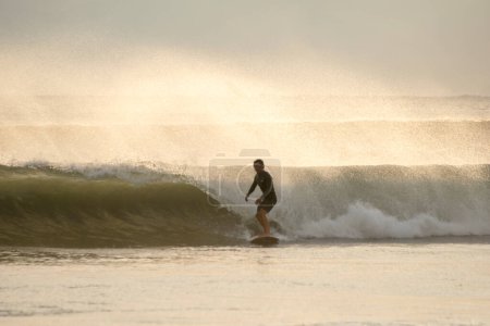 Téléchargez les photos : Surfeur chevauchant une vague de mer au coucher du soleil, loisirs actifs - en image libre de droit