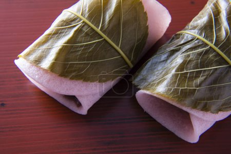 Téléchargez les photos : Sakuramochi est une confiserie japonaise (wagashi) composée d'un gâteau de riz doux de couleur rose (mochi) avec de la pâte de haricot rouge (anko), enveloppé dans une feuille de fleur de cerisier marinée (sakura) - en image libre de droit