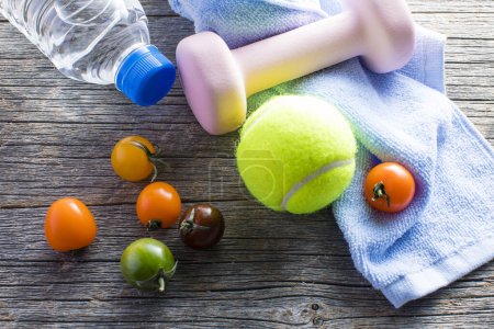 Téléchargez les photos : Tomates, verre d'eau, serviette, balle de tennis et haltère sur table en bois - en image libre de droit
