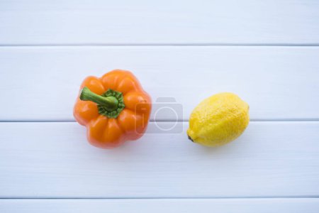 Foto de Pimiento naranja y limón sobre fondo blanco de madera - Imagen libre de derechos